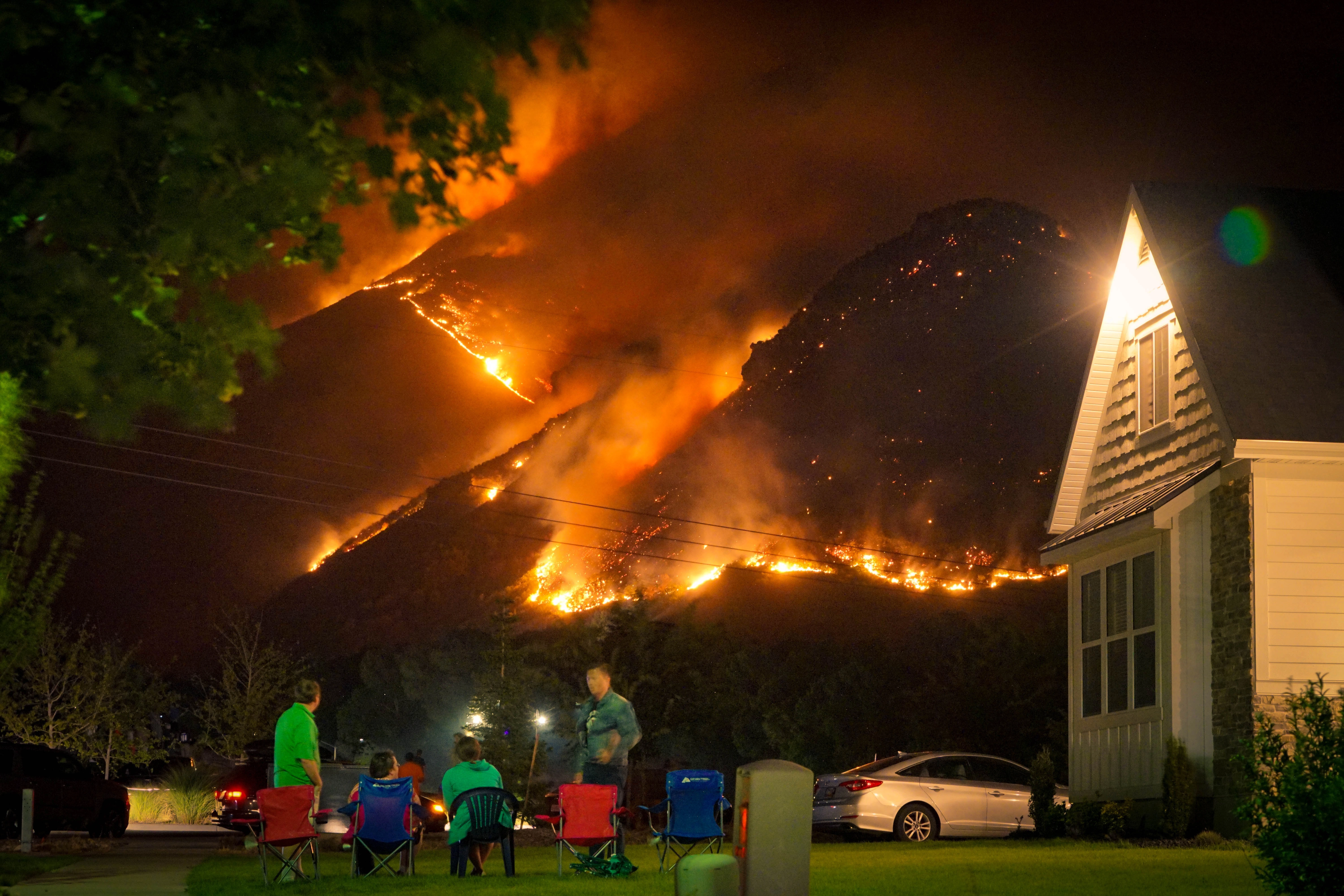 A family watches a nearby wildfire from their front lawn